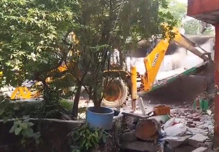 हरथला में मुरादाबाद-हरिद्वार हाईवे पर मज़ार हटाते हुए बुलडोजर और मौजूद पुलिस बल